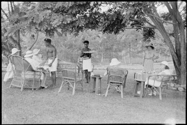 Six women with two men serving tea in Chinnery's garden, Malaguna Road, Rabaul, New Guinea, ca. 1935 / Sarah Chinnery