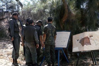 A group of Air Force security policemen gather around SSGT Richard Bishop, a Marine Corps instructor, as he briefs them on the details of an anti-terrorist operation. The policemen are participating in an anti-terrorist exercise being conducted by the 1ST Marine Brigade School