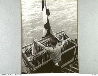 1943-07-12. AMERICAN ADVANCE INTO TROBRIAND ISLANDS. A SIGNALMAN ON ONE OF THE ESCORTING VESSELS OF THE CONVOY TO KIRIWINA ISLAND PREPARES TO HOIST A SIGNAL TO OTHER ESCORTING WARSHIPS. (NEGATIVE ..