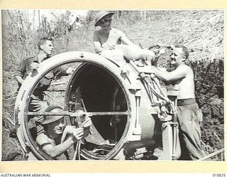 1943-09-25. NEW GUINEA. FALL OF LAE. AROUND A DAMAGED JAPANESE MOBILE SEARCHLIGHT ABANDONED AT LAE ARE SGT. BERT HARKNESS OF GLENELG, SOUTH. AUSTRALIA, PADRE E. A. JAMES OF MELBOURNE, VIC., PTE. J. ..