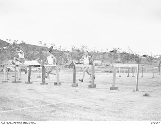 PORT MORESBY, NEW GUINEA. 1944-04-23. COMPETITORS CLEARING THE LAST HURDLE DURING THE 100 YARDS HURDLE RACE IN THE 2/101ST GENERAL TRANSPORT COMPANY SPORTS MEETING HELD AT 9 MILE. IDENTIFIED ..