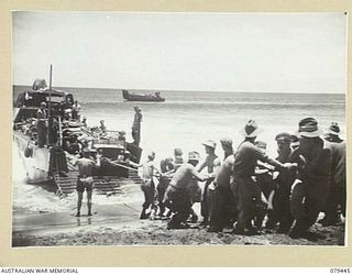 BOUGAINVILLE ISLAND. 1945-03-06. TROOPS OF HEADQUARTERS, 7TH INFANTRY BRIGADE HAULING A JEEP OFF A BARGE AT TOKO AFTER A WAVE BREAKING OVER IT HAD STALLED THE MOTOR
