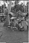 Mortuary ceremony, Omarakana: mourning women and children carry fiber skirts and baskets of banana leaf bundles for ritual exchange