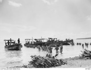 RABAUL, NEW BRITAIN. 1945-09-30. JAPANESE TROOPS WADING OUT TO JAPANESE BRAGES CARRYING MACHINE-GUNS FOR DUMPING INTO THE SEA UNDER 28 INFANTRY BATTALION SUPERVISION