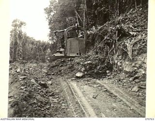 WAMPIT, NEW GUINEA. 1944-03-01. A D8 ANGLEDOZER REEFING THE BANK 64 1/2 MILES FROM WAU ON THE WAU - LAE ROAD SECTION. THE ROAD IS IN AN OPERATIONAL AREA OF HEADQUARTERS, COMMANDER ROYAL ENGINEERS ..