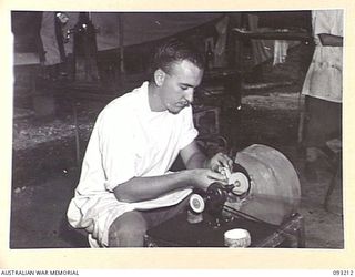 JACQUINOT BAY, NEW BRITAIN, 1945-06-16. CPL F.J. CASHMAN, 77 DENTAL UNIT (AIF) POLISHING UP A SET OF DENTURES