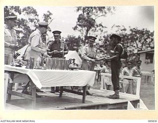 HERBERTON, QLD. 1945-01-19. CORPORAL H OSKINS, 2/2 MACHINE GUN BATTALION, (6), RECEIVES HIS PRIZE FROM LIEUTENANT GENERAL SIR LESLIE J MORSHEAD, GENERAL OFFICER COMMANDING 1 CORPS, (5), AT THE 9 ..