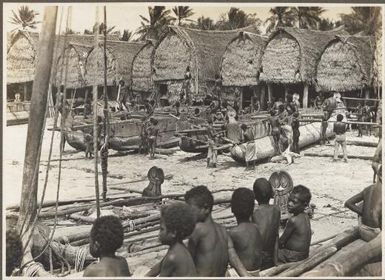 Scene in  Mailu Village [men working on canoes]