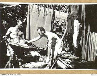 FINSCHHAFEN AREA, NEW GUINEA, 1943-10-28. NX81590 PRIVATE W.H. THOMAS OF RANDWICK, NSW (LEFT) AND NX30186 WARRANT OFFICER II. J. PERRY OF RANDWICK, NSW, BOTH COOKS OF THE 2/2ND AUSTRALIAN MACHINE ..