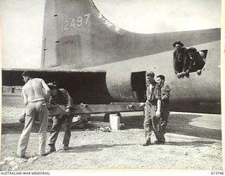 1942-12-07. NEW GUINEA. A 105MM M-3A1 HOWITZER COMPLETE WITH SPARES, TRACTOR AND AMMUNITION IS UNLOADED SOMEWHERE IN THE BATTLE AREA. THE GUN CREW ALSO CAME WITH THE GUN. PICTURE SHOWS A PORTION OF ..