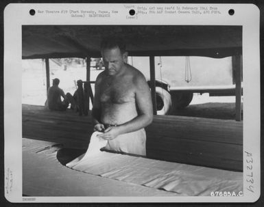 A "GI" of the 27th Air Depot Group cuts airplane fabric at the dope and fabric shop, Port Moresby Air Depot, Papua, New Guinea. 1943. (U.S. Air Force Number 67685AC)