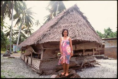 Woman outside house with thatched roof, Cook Islands