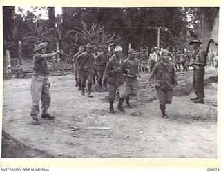 TOROKINA, BOUGAINVILLE. 1945-09-23. JAPANESE NAVAL TROOPS MOVING AT THE DOUBLE INTO A SEARCHING HUT FOR SEARCHING BY OFFICERS OF 9 INFANTRY BATTALION, AT THE CONCENTRATION CAMP, CHOP CHOP TRAIL. ..