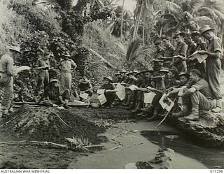 NEW GUINEA. 15 JUNE 1944. AUSTRALIAN OFFICERS CONFERRING WITH U.S. ENGINEERS PREPARATORY TO THE LANDING ON KARKAR ISLAND WHICH WAS OCCUPIED BY THE AUSTRALIANS WITHOUT RESISTANCE. A MUDMAP IS ..