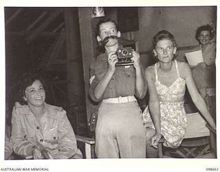 LAE, NEW GUINEA. 1945-11-08. PRIVATE L. CARTER IMPERSONATING AN OFFICIAL MILITARY HISTORY PHOTOGRAPHER AT THE FANCY DRESS PARTY HELD BY MEMBERS OF AUSTRALIAN WOMEN'S ARMY SERVICE BARRACKS TO ..