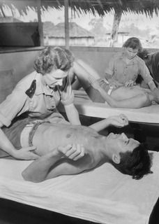 Lae, New Guinea. 1944-08-02. Lieutenant (Lt) N. W. Davies (1) and Lt D. F. Kay (2), Physiotherapists, assisting patients with their exercises at 2/7th Australian General Hospital