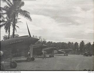 MOMOTE, LOS NEGROS ISLAND, ADMIRALTY ISLANDS. 1944-03-08. KITTYHAWK AIRCRAFT OF NO. 77 SQUADRON RAAF ON STAND-BY AT MOMOTE AIRSTRIP, BESIDE THE PALM TREES, SCENE OF THE ORIGINAL LANDING IN THE ..