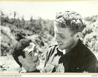 1943-03-03. PAPUA. JAPANESE UNSUCCESSFULLY ATTACK WAU. PRIVATE MICHAEL FILL AND HERBERT HIS VENTRILOQUIST'S DUMMY, ENTERTAIN HIS MATES AT WAU AERODROME DURING A RESPITE IN THE FIGHTING