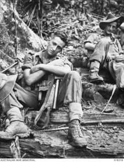 Aitape, New Guinea. 1945-03-02. Fatigued after his strenuous climb up the "Golden Stairway" Private Fred Westland of Melbourne, Vic, rests on one of the steps and reclines on his Owen gun