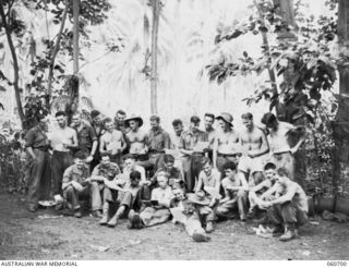 FINSCHHAFEN, NEW GUINEA. 1943-10-30. A GROUP OF THE 26TH AUSTRALIAN INFANTRY BRIGADE SIGNALS SECTION READING THE LATEST NEWS SHEET. SHOWN ARE: VX19886 CORPORAL W. H. E. SHAW (1). NX65970 SIGNALMAN ..