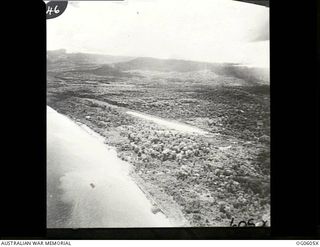 New Guinea. Aerial view of terrain along the coast showing thick vegetation either side of an airfield landing strip