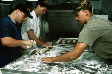 Navy and Marine mess management specialists aboard the amphibious assault ship USS SAIPAN (LHA-2) make cookies in preparation for the arrival of evacuees from the U.S. Embassy in Monrovia, Liberia. The SAIPAN is on station off the coast of Liberia for Operation Sharp Edge