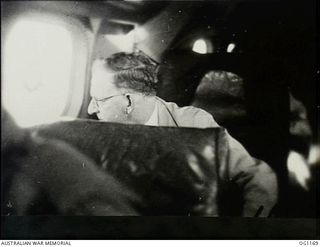 IN FLIGHT BETWEEN HOLLANDIA, DUTCH NEW GUINEA AND AITAPE, NORTH EAST NEW GUINEA. C. 1944-06. ARTHUR DRAKEFORD, THE MINISTER FOR AIR, LOOKING THROUGH THE WINDOW OF THE AIRCRAFT, DURING THE ..