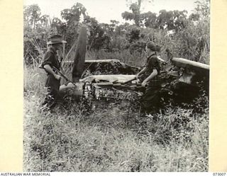 MADANG, NEW GUINEA. 1944-04-25. AUSTRALIAN TROOPS EXAMINING THE WRECKAGE OF AN AIRCRAFT. IT IS ONE OF MANY WRECKED AIRCRAFT AT THE NEWLY CAPTURED AIRFIELD