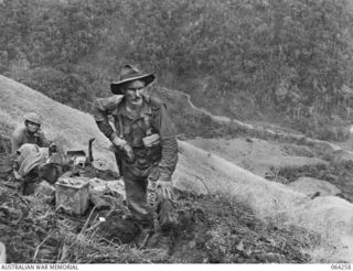 NX10251 LIEUTENANT E.V. STEPHENSON (FOREGROUND) OF "A" COMPANY, 2/9TH INFANTRY BATTALION AND QX54942 SIGNALMAN J.J. O'CONNOR (LEFT BACKGROUND) AT A NEWLY ESTABLISHED SIGNAL POST DURING THE BATTLE ..
