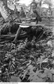 TAMIGUDU, NEW GUINEA. 1944-05-12. A NATIVE WITH A BOAT HE HAD MADE. THE NATIVES MAKE A VARIETY OF SOUVENIRS WHICH HAVE A READY SALE AMONG TROOPS IN THE AREA