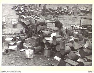 WEWAK POINT, NEW GUINEA. 1945-09-28. PRIVATE J.R. NICHAREN, 2/8 INFANTRY BATTALION, SELECTS HIS "SEAT" IN THE "FOYER" BEFORE THE PERFORMANCE BY THE DARYA COLLIN BALLET TROUPE AT THE THEATRE ERECTED ..