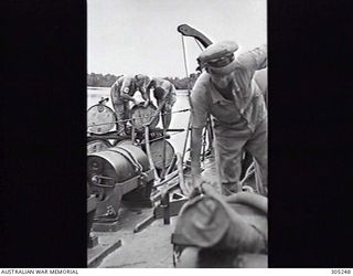 MADANG, NEW GUINEA. 1944. AVIATION SPIRIT ABANDONED BY JAPANESE AT THE AIRSTRIP BEING USED TO REFUEL HMA MOTOR LAUNCH ML424. NOTE THE DEPTH CHARGE LASHED TO THE RACK AT LEFT. (NAVAL HISTORICAL ..