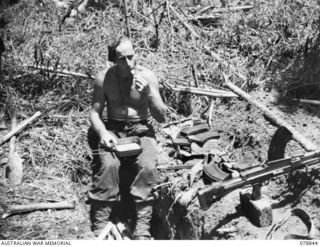 BOUGAINVILLE ISLAND. 1945-01-31. N34913 PRIVATE L. FLEMING, BREN GUNNER, "B" COMPANY, 9TH INFANTRY BATTALION, ENJOYING A HOT MEAL IN HIS FOXHOLE DURING A LULL IN THE FIGHTING IN THE AREA