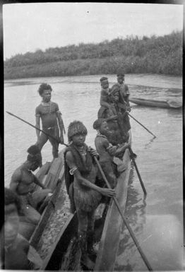 Ten people standing in two canoes, some holding poles, Ramu River, New Guinea, 1935 / Sarah Chinnery
