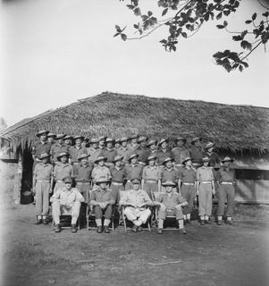 LAE, NEW GUINEA. 1944-08-28. VX13 LIEUTENANT-GENERAL S.G. SAVIGE, CB, CBE, DSO, MC, ED, GENERAL OFFICER COMMANDING, NEW GUINEA FORCE (3) WITH MEMBERS OF THE REGIMENT OUTSIDE THE MESS HUT OF NO. 22 ..