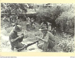 BOGIA, NEW GUINEA. 1944-07-30. T102546 PRIVATE K.S. ARNOLD (1), N378137 PRIVATE N.J. CLACK (2) OF THE 30TH INFANTRY BATTALION CLEANING THEIR BREN GUN ON THE BANK OF A CREEK WHILE THEIR FELLOW ..