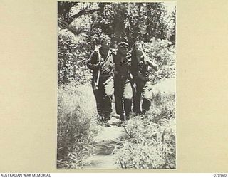 BOUGAINVILLE ISLAND, 1945-01-21. NX76537 CAPTAIN B. SHORT, MEDICAL OFFICER (1) AND QX62740 PRIVATE M. CASE (2) ASSISTING WX39661 PRIVATE R.C. CARTER ALONG THE MAWARAKA MOSIGETTA ROAD TO THE ..