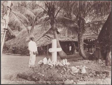 Man standing next to a memorial cross for the Christian pioneer of Guadalcanar, Maravovo, Solomon Islands, 1906 / J.W. Beattie