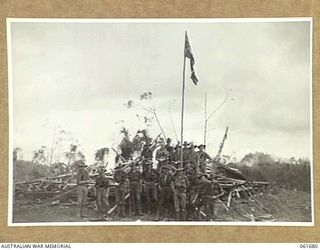 WAREO, NEW GUINEA. 1943-12. IDENTIFIED PERSONNEL ARE: GROUP OF OFFICERS AND MEN OF THE 2/23RD AUSTRALIAN INFANTRY BATTALION, AROUND THE UNIT VICTORY FLAG. THIS FLAG WAS PREVIOUSLY RAISED OVER ..