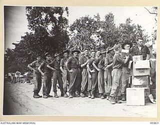 WEWAK AREA, NEW GUINEA, 1945-07-05. CORPORAL L.A. BEGLEY, C COMPANY, 2/8 INFANTRY BATTALION (1) HANDING OUT THE MID-YEAR AUSTRALIAN COMFORTS FUND HAMPERS TO MEMBERS OF THE UNIT AT UNIT REST CAMP ON ..
