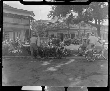 Road scene, Papeete, Tahiti, showing a man trimming hedge and other local men talking