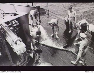 FINSCHHAFEN, NEW GUINEA, 1944. RAN PERSONNEL SCRUBBING THE FO'C'S'LE OF HMAS CASTLEMAINE. (DONOR: J. DEEBLE)