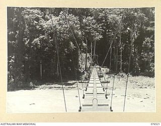 LAE, NEW GUINEA. 1944-10-18. THE SUSPENSION BRIDGE BUILT ACROSS THE BUSU RIVER BY MEMBERS OF THE 20TH FIELD COMPANY TO CARRY A SIX INCH PIPELINE FROM A NEW RESERVOIR TO SUPPLY WATER TO THE 2/7TH ..