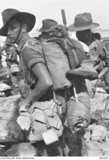 AITAPE BEACH, NEW GUINEA. 1944-11-26. PRIVATE A.W. TEAGUE, 6 DIVISION, (1), MOVING ASHORE FROM A LANDING BARGE