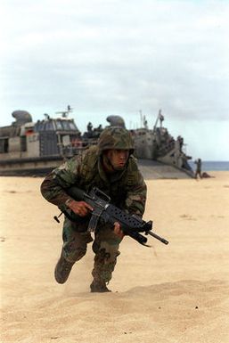 With a determined look on his face, LCPL Donald Retreage of the1st Light Armored Reconnaissance, Camp Pendleton, California participates in the beach assault during exercise RIMPAC '98. In the background is a Landing Craft, Air Cushion which brought the Marines to the beach