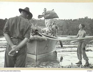 JACQUINOT BAY, NEW BRITAIN. 1944-11-14. PERSONNEL OF HEADQUARTERS, 5TH DIVISION LOADING THE UNIT MAIL INTO A MOTOR LAUNCH FOR DISTRIBUTION TO THE SUB UNITS IN THE AREA