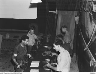 TOROKINA, BOUGAINVILLE, 1945-12-05. MEMBERS OF CINEMA STAFF OF 1 DETACHMENT MOBILE CINEMA UNIT, REVIEWING FILMS IN THE WINDING ROOM