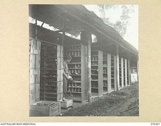 LAE, NEW GUINEA. 1944-09-27. A MEMBER OF THE 43RD FIELD ORDNANCE DEPOT CHECKING THE SUPPLIES OF SPARE PARTS IN THE RACKS OF ONE OF THE UNIT STORES