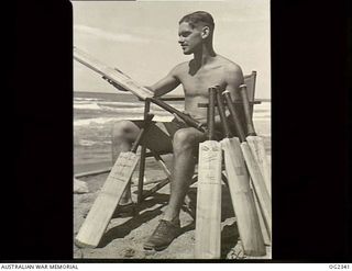 AITAPE, NORTH EAST NEW GUINEA. 1945-03-30. 419691 FLYING OFFICER (FO) JACK SULLIVAN OF KEW, VIC, A NAVIGATOR OF A RAAF BEAUFORT BOMBER AIRCRAFT, DURING A REST PERIOD LOOKS OVER SOME NEW CRICKET ..