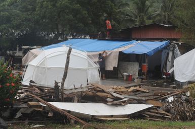 Earthquake ^ Flooding ^ Tsunami - Pago Pago, American Samoa, October 15, 2009 -- Family members have cleared debris and are busily making repairs to their home in the rain. The Federal Emergency Management Agency provided tents as temporary shelter until the habitability can be restored to their home. David Gonzalez/FEMA